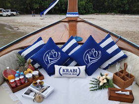 A beautifully arranged seating area on a longtail boat featuring tropical fruits, drinks, and decorative pillows — perfect for a relaxing day on the water.