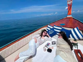 Two friends relax on the deck of a boat under the sun, enjoying a serene day on the water — perfect for a leisurely getaway.