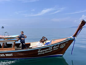 Two guests enjoy a sunny day aboard a traditional boat, showcasing the beauty of the sea and the joy of exploration.