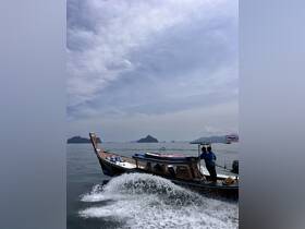 A traditional longtail boat navigates through calm waters, showcasing stunning scenery and the thrill of adventure on the open sea.