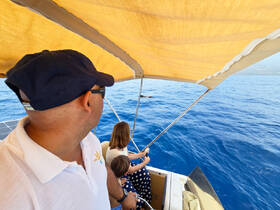 A family enjoys a day on the water, with one adult and a child engaged in fishing while taking in the beautiful ocean views.