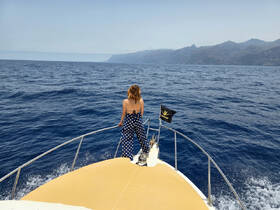 A woman enjoys the stunning ocean view from the bow of a boat, capturing the essence of adventure and exploration on the open water.