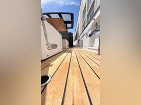 A detailed view of the wooden deck and helm area inside a boat, showcasing the sleek design and spacious layout ideal for comfortable cruising.