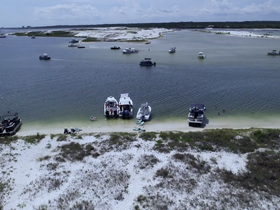 A scenic view of multiple boats anchored at a sandbar, with guests enjoying the water and beach activities — a perfect summer getaway.