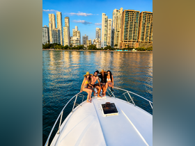 A lively group of friends enjoys a sunny day on the bow of a boat, with a stunning cityscape backdrop — perfect for unforgettable moments on the water.