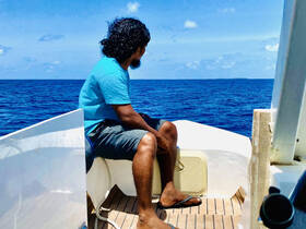 A man enjoys a moment of tranquility aboard a boat, gazing out at the vast ocean — perfect for those seeking relaxation on the water.
