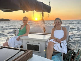 Two women enjoy a beautiful sunset aboard a yacht, capturing the essence of relaxation and celebration on the water.