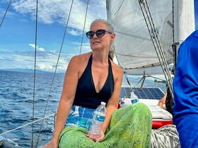 A woman enjoys a relaxing moment aboard a sailboat, surrounded by the beautiful ocean scenery — perfect for sailing adventures.