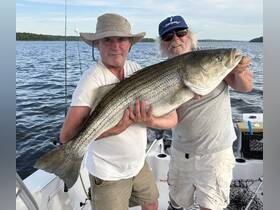 Two anglers proudly display their impressive catch while fishing on a boat, showcasing the thrill of a successful day on the water.