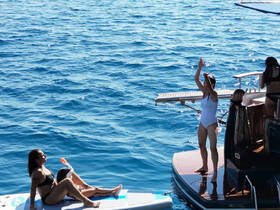 A lively scene on the water with friends enjoying a day on a boat, featuring swimming and snorkeling activities — perfect for summer adventures.