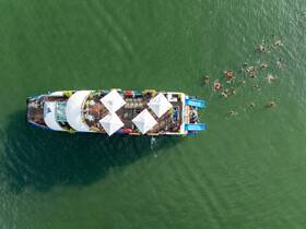 A vibrant scene of guests enjoying water activities around a boat, showcasing a lively atmosphere perfect for group fun and celebrations.