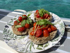 A delicious plate of fresh tomato and arugula snacks served on a boat, perfect for enjoying while cruising on the water.