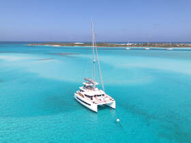 A stunning aerial view of a catamaran anchored in crystal-clear turquoise waters, showcasing the beauty of a serene boating experience.