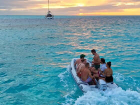 A lively group enjoys a sunset ride on a dinghy, creating unforgettable memories on the water — perfect for social gatherings and adventures.