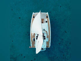 Aerial view of a sleek catamaran sailing over crystal-clear waters, showcasing its elegant design and perfect for serene ocean adventures.