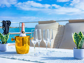 A stylish setup featuring a golden champagne bucket and elegant glasses, perfect for enjoying cocktails on a luxurious yacht. Ideal for celebrations and relaxing moments on the water.