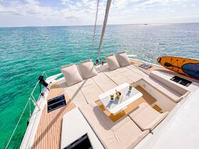 A beautifully arranged lounge area on a yacht's deck, featuring comfortable seating and a paddleboard, perfect for relaxation and enjoying cocktails on the water.