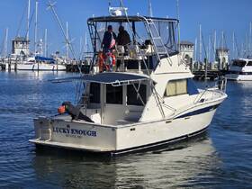 The fishing boat 'Lucky Enough' is docked in Biloxi, MS, with guests preparing for a day on the water, showcasing the vibrant marina atmosphere.