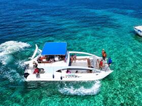A lively group enjoys a day on a catamaran, surrounded by stunning turquoise waters — perfect for fun and adventure on the high seas.