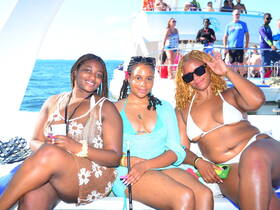Three friends enjoy a vibrant boat party, soaking up the sun and celebrating together on the water — a perfect moment for fun and relaxation.