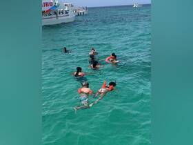 A lively group enjoys snorkeling in the clear turquoise waters, showcasing the fun and adventure of underwater exploration.