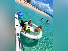 A lively group enjoys a fun day in the turquoise waters, relaxing on a floating mat with drinks in hand — the perfect beach party experience.