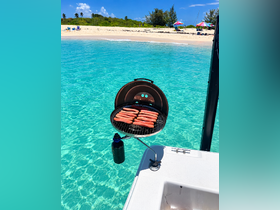 A grill with hot dogs is set up on a boat, overlooking a stunning turquoise bay — perfect for a day of fun and relaxation on the water.
