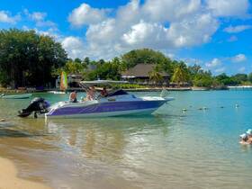 A family enjoys a sunny day at the beach with a vibrant boat anchored nearby, perfect for a tropical getaway.