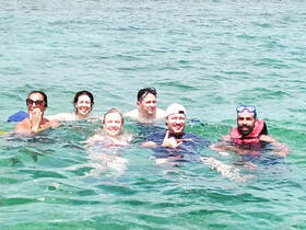 A lively group enjoys a refreshing swim in clear waters, showcasing the fun and excitement of a snorkeling adventure.