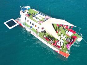 A vibrant group enjoys a lively day on a spacious party boat, complete with lounging areas and a swimming platform, perfect for summer fun on the water.