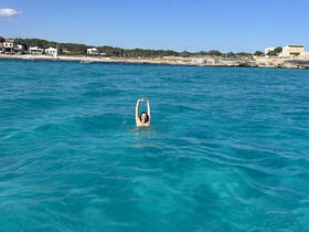 A joyful swimmer enjoys the crystal-clear waters, showcasing the perfect beach day experience.