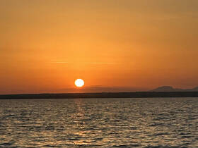 A serene sunset over calm waters, creating a picturesque backdrop perfect for evening boat cruises.