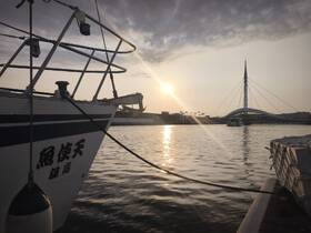 A serene view of a boat docked at sunset, showcasing its structure against a picturesque backdrop of the water and a modern bridge.