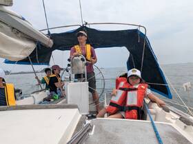A family enjoys a sailing adventure, with children wearing life jackets while taking in the views on the boat. Perfect for family outings on the water.