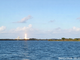 A stunning view of a rocket launch over the water, capturing the excitement of space exploration against a picturesque sky.