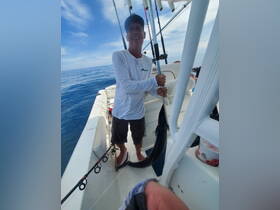 A fisherman proudly displays his catch aboard a boat, showcasing the thrill of fishing on the open ocean.