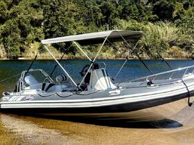 A sleek speedboat docked by the shore, showcasing its modern design against a lush green backdrop — perfect for water adventures.