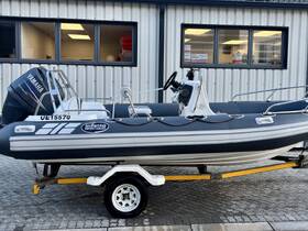 A sleek inflatable boat with a Yamaha engine, showcased on a trailer in front of a facility — perfect for exploring coastal waters.