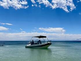 A scenic view of a boat anchored in clear waters, with guests enjoying the beautiful day under a vibrant sky — perfect for a relaxing day on the water.