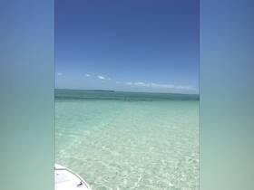 A serene view of clear turquoise waters with a glimpse of a boat's bow, perfect for showcasing the beauty of a day on the water.