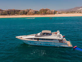An aerial view of a luxurious yacht anchored in vibrant turquoise waters, showcasing the stunning coastline and nearby beach resorts — perfect for upscale boating experiences.