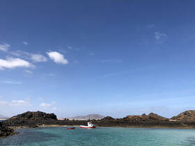A scenic view of a small boat anchored near rocky shores under a clear blue sky, perfect for exploring coastal waters.