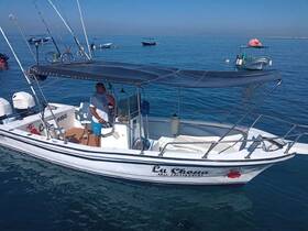 A fishing boat named 'La Chona' is seen on calm waters, with a captain at the helm, showcasing a perfect day for fishing or leisure on the sea.