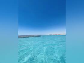A stunning view of crystal-clear turquoise waters with people enjoying the scenery, perfect for a day of relaxation and exploration in a tropical paradise.