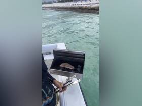 A person prepares a delicious steak on the grill aboard a boat, showcasing the perfect setup for a barbecue on the water.