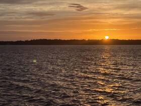 A serene sunset over calm waters, creating a picturesque backdrop perfect for evening boat cruises.