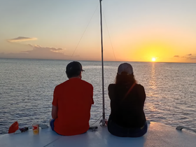 A couple enjoys a romantic sunset view from the deck of a boat, creating a perfect backdrop for memorable moments on the water.