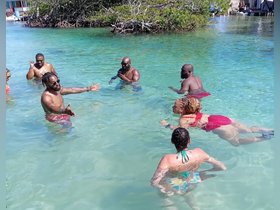 A lively group enjoys a fun day in the clear waters, engaging in conversation and swimming — perfect for memorable celebrations and group outings.
