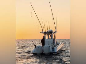 A fishing boat heads out into the ocean at sunset, with rods ready for an evening of angling adventure. Perfect for fishing enthusiasts looking to enjoy the serene waters.
