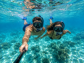 A couple enjoys snorkeling in crystal-clear waters, exploring vibrant coral reefs — a perfect adventure for ocean lovers.
